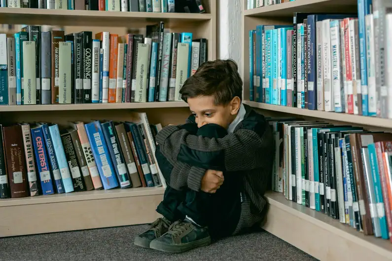 dziecko skulone w kącie biblioteki